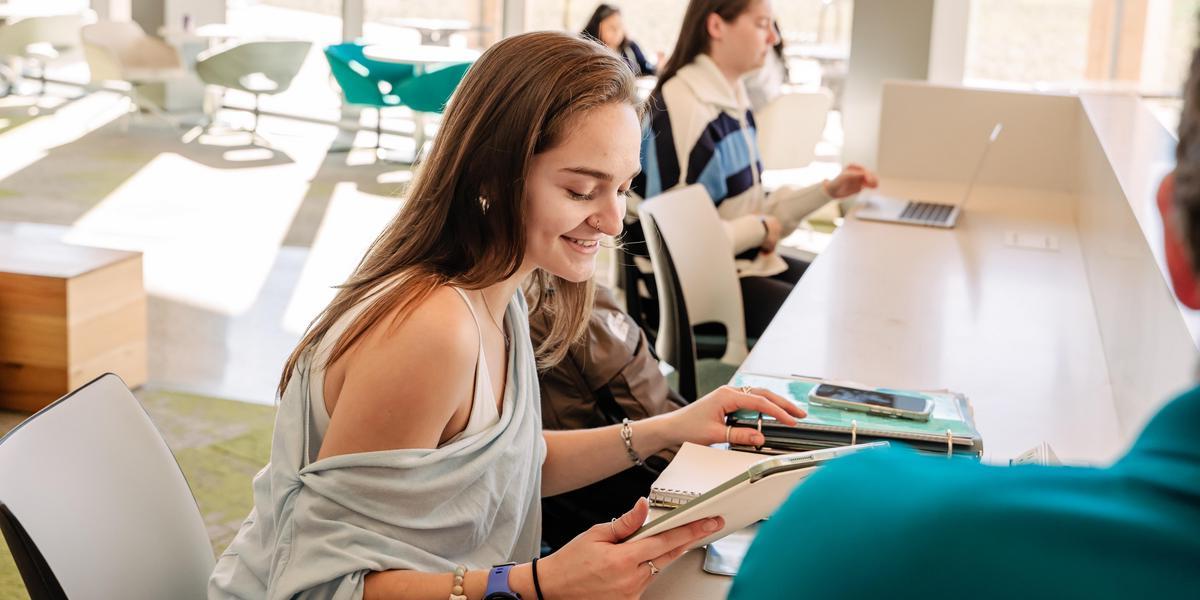 Student looking at tablet and notebook.